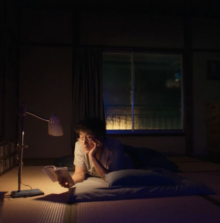 Un hombre tumbado en el suelo leyendo un libro