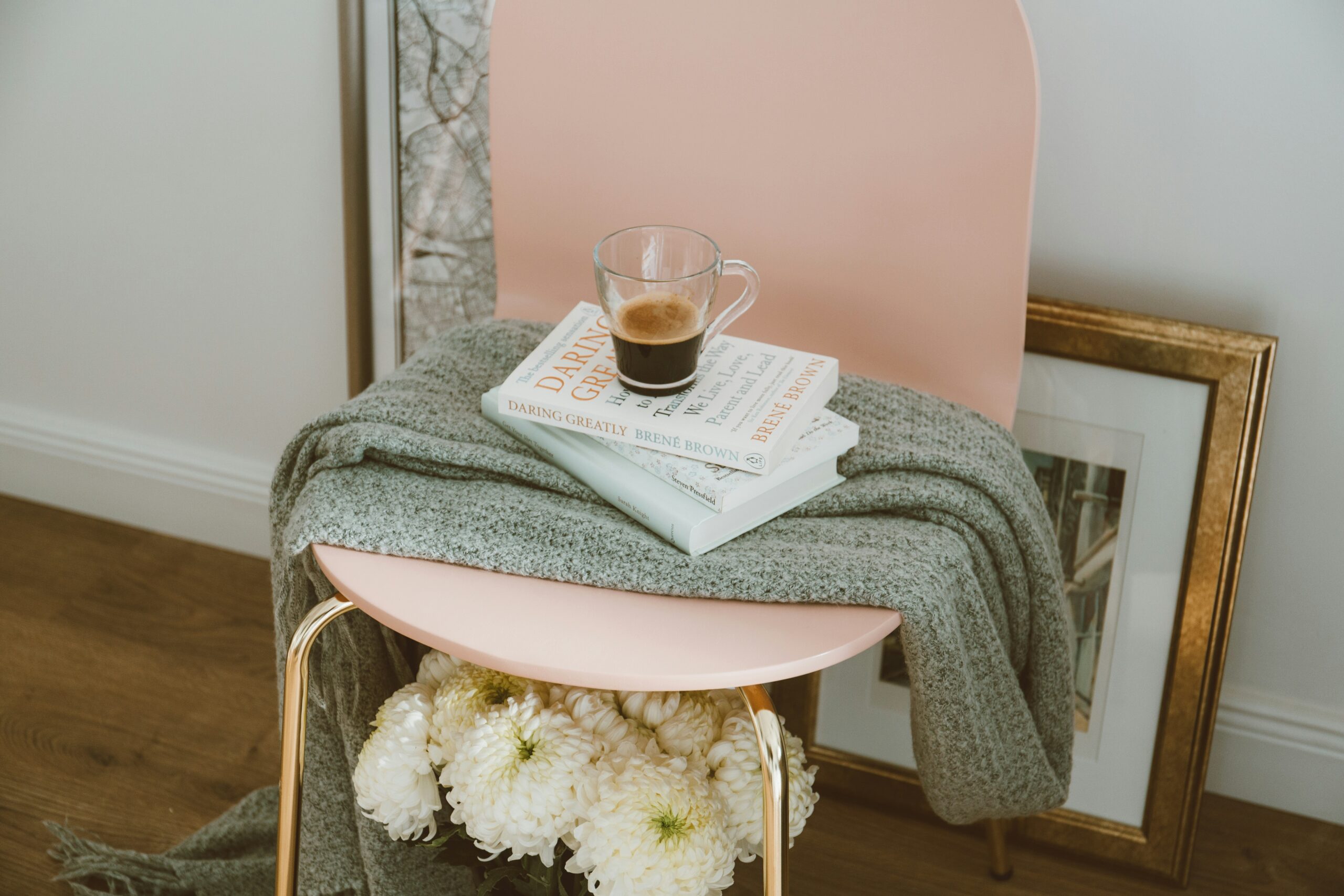 Una silla rosa con libros posados en ella y encima una taza de café